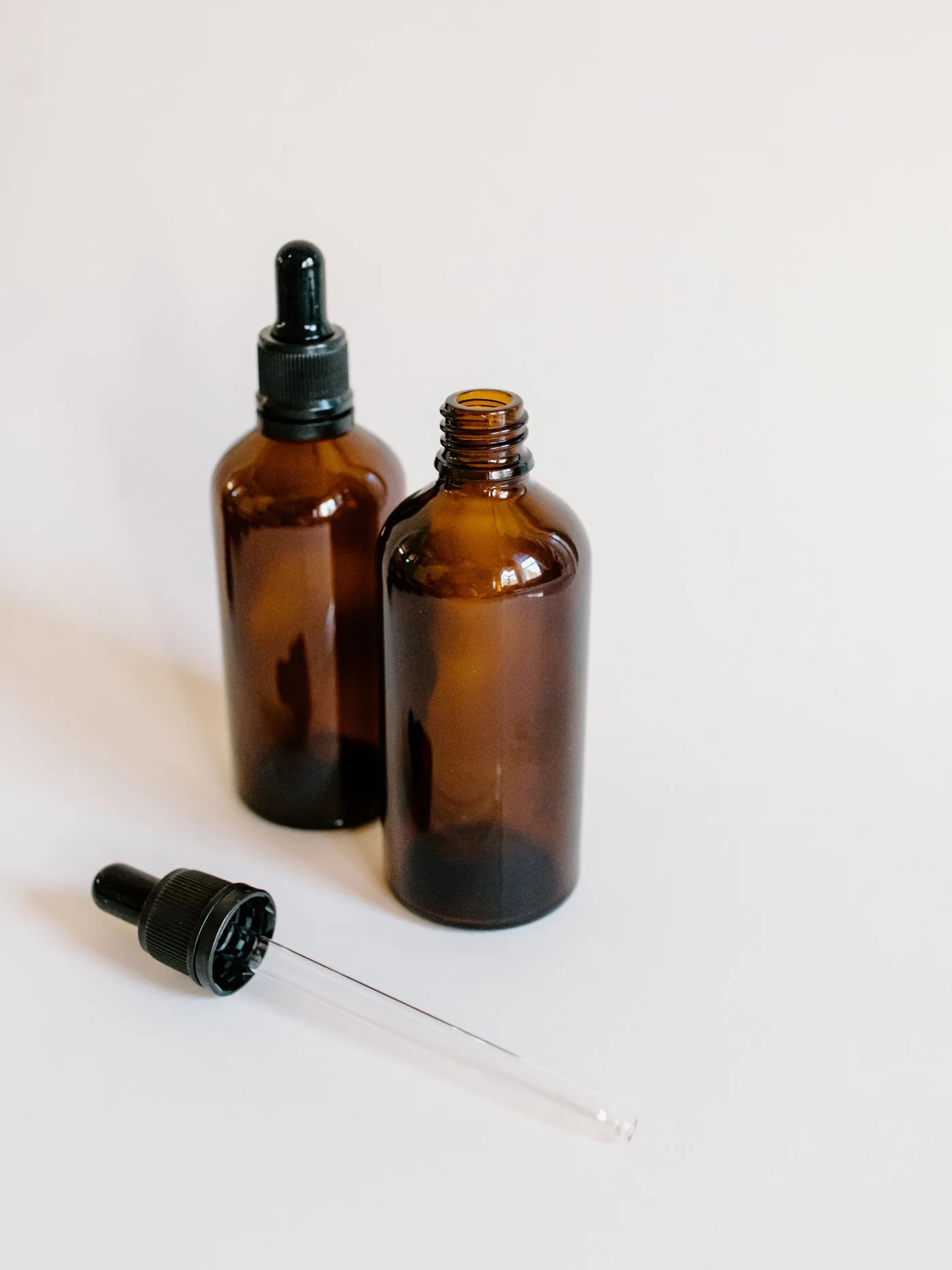 Two amber glass bottles and a dropper on a white background
