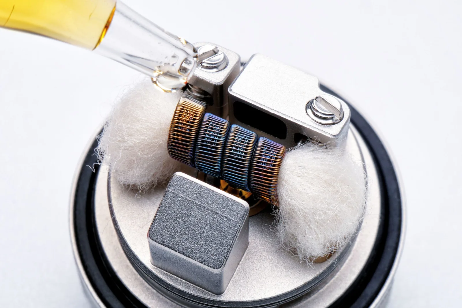 A dropper wetting the cotton around a coil on a metal deck