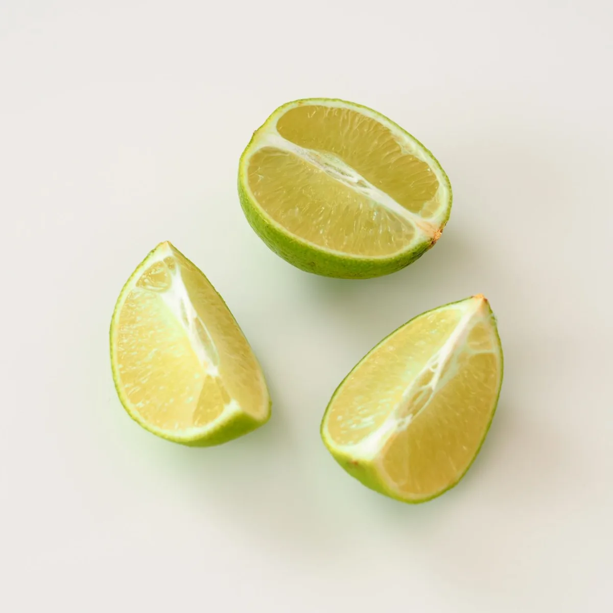 Three lime wedges on a white surface