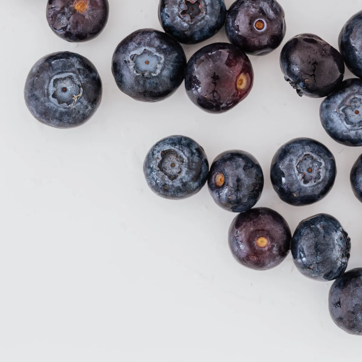 Fresh blueberries scattered on a white surface